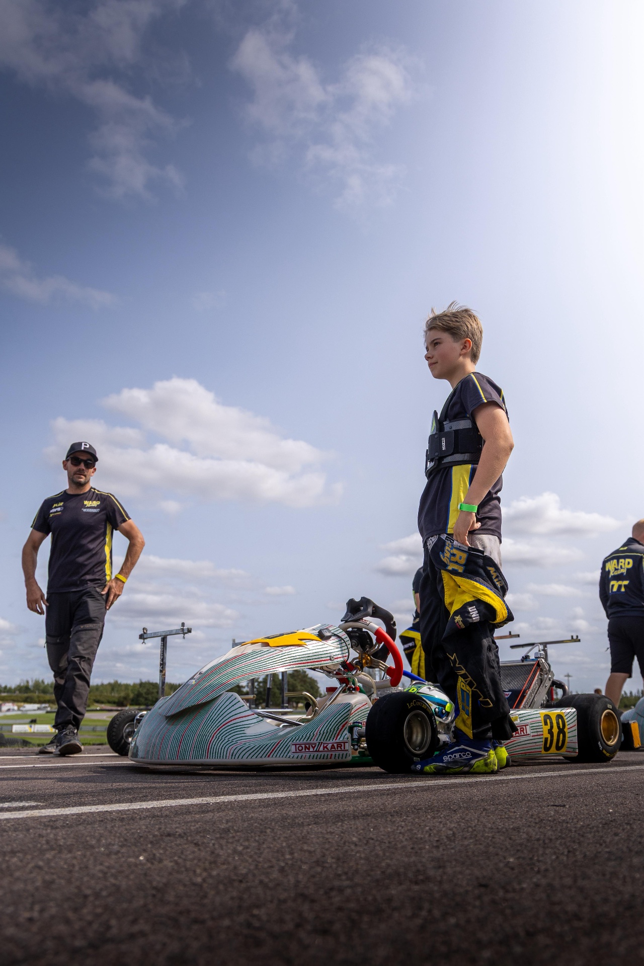 Kevin Pentell standing next to his kart, race suit half-down